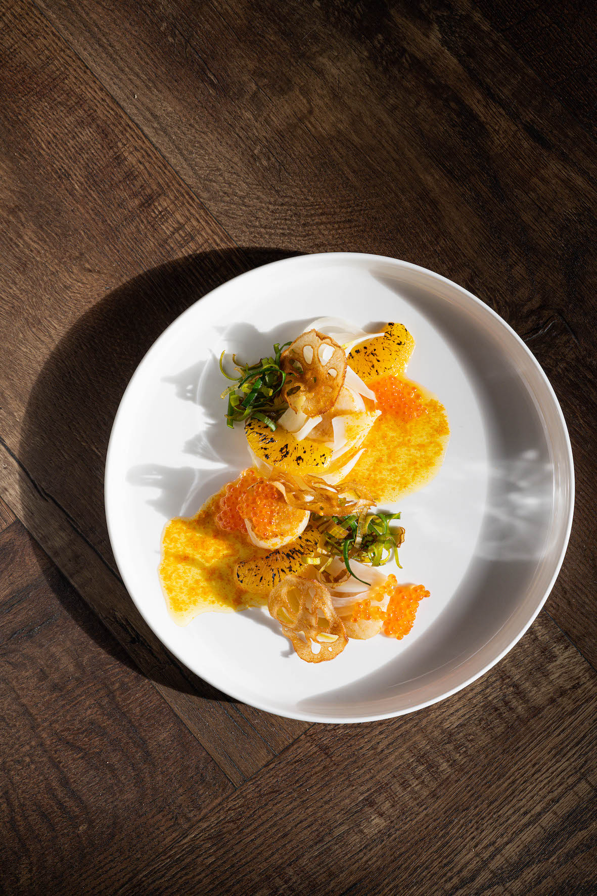 Coquilles met kruidenboter, saffraan, gefrituurde prei, lotuswortel, gebrande sinaasappel & foreleitjes