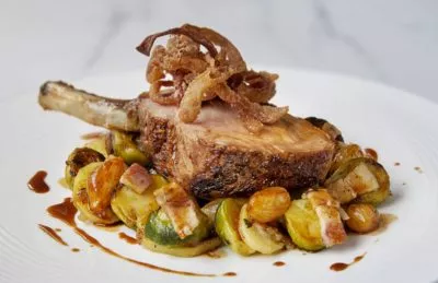 Varkensribstuk met spruiten en spek, pommes boulangères en gefruite varkensoor